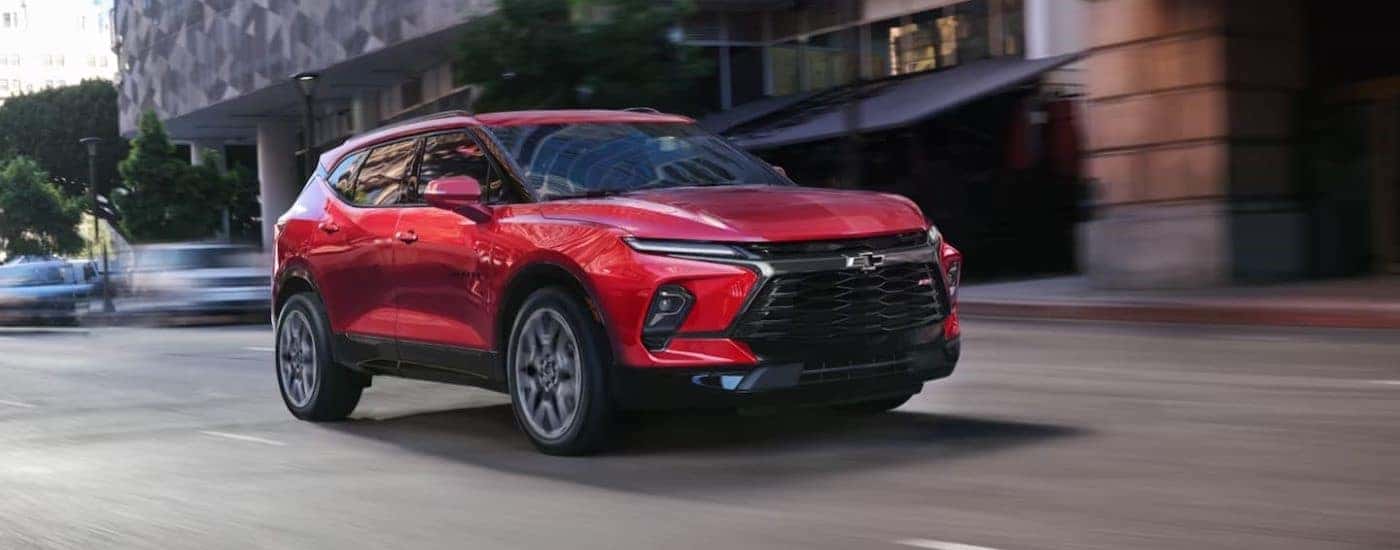 A red 2023 Chevy Blazer RS is shown driving on a city street.