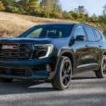 A black 2025 GMC Acadia Elevation parked off-road on gravel