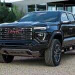 A black 2026 GMC Canyon parked off-road on gravel