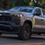 Silver 2026 Chevy Colorado driving down a road.
