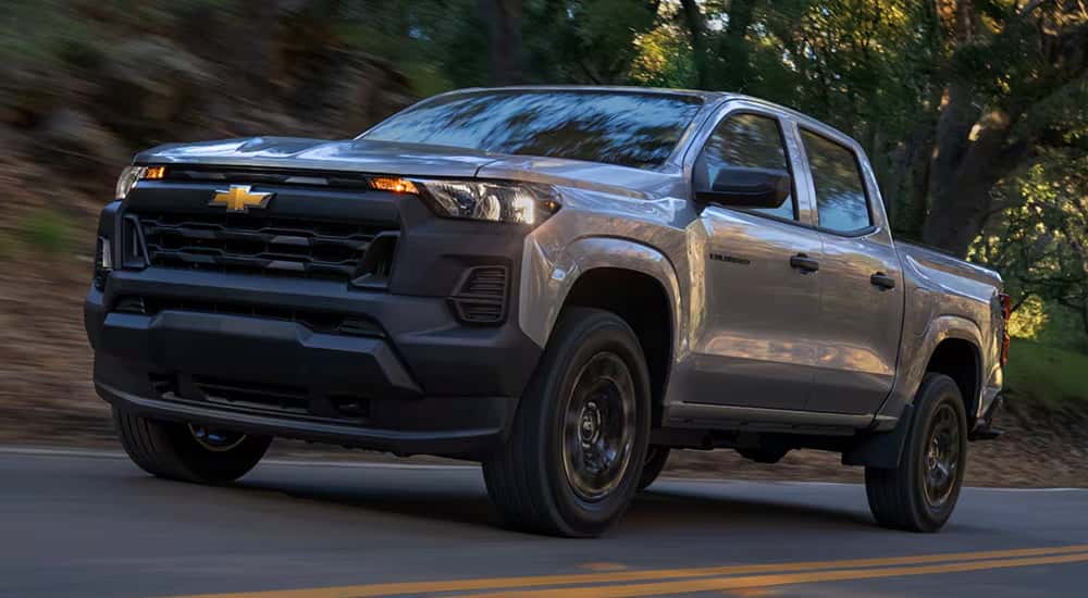 Silver 2026 Chevy Colorado driving down a road.