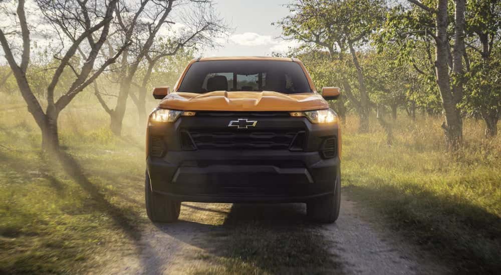 Front of a yellow 2026 Chevy Colorado driving down a road.