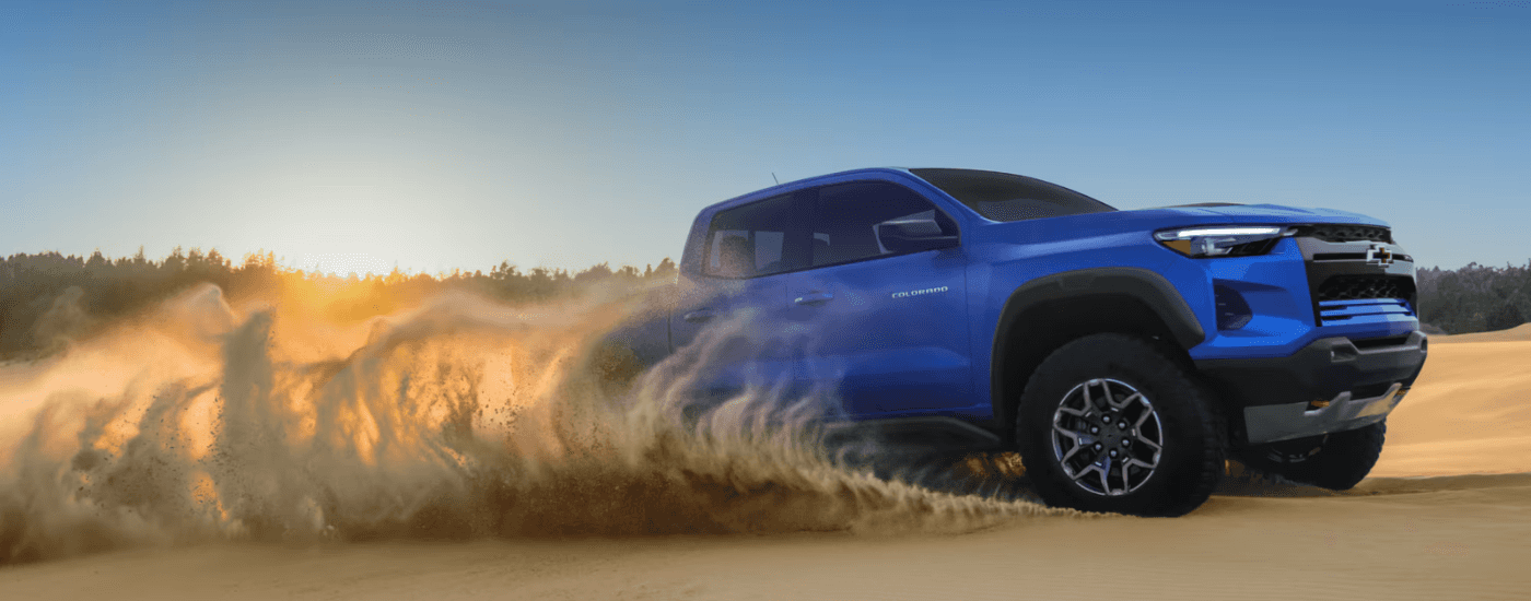 Blue 2026 Chevy Colorado driving on a sand dune