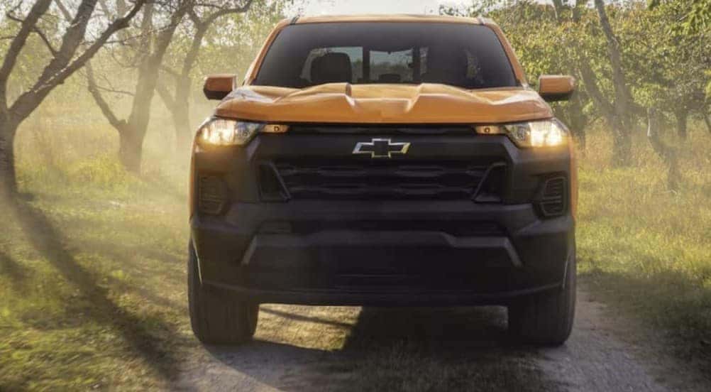 A yellow 2026 Chevy Colorado driving on a trail.