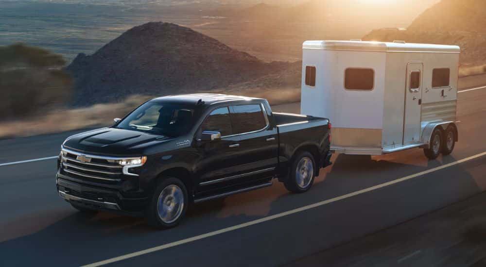 Black 2026 Chevy Silverado 1500 towing a trailer down the road