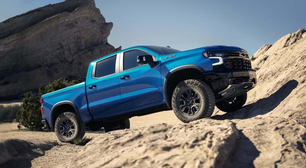 Blue 2026 Chevy Silverado 1500 driving up rocks