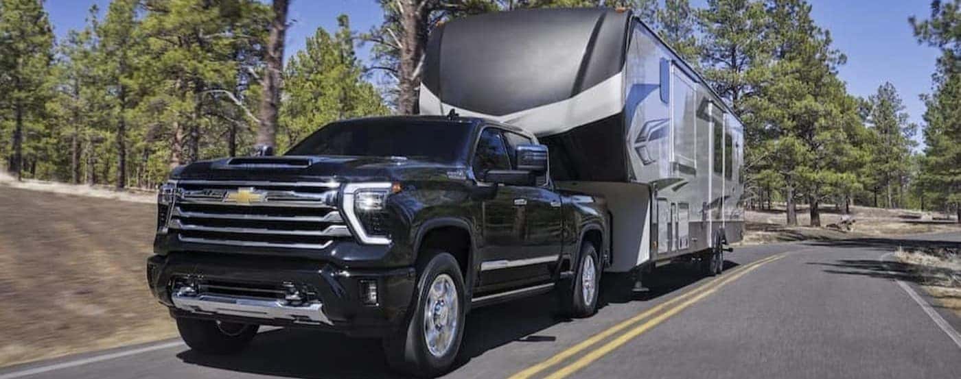A black 2026 Chevy Silverado 3500 towing a trailer.