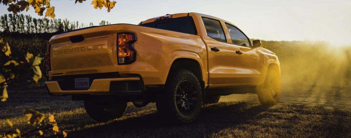 A sunrise orange Chevy Colorado WT parked in a field rear-facing.
