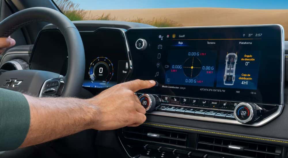 Close up of a 2026 Chevy Colorado's infotainment system with driver selecting a program.