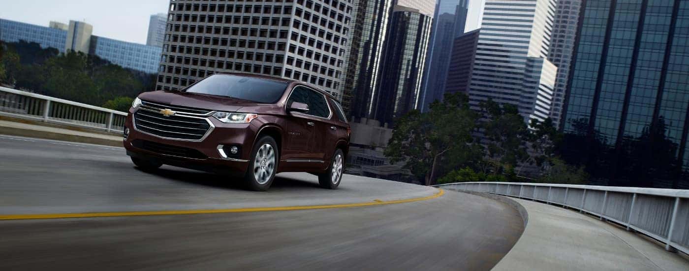 A maroon 2019 Chevy Traverse shown driving away from a city.