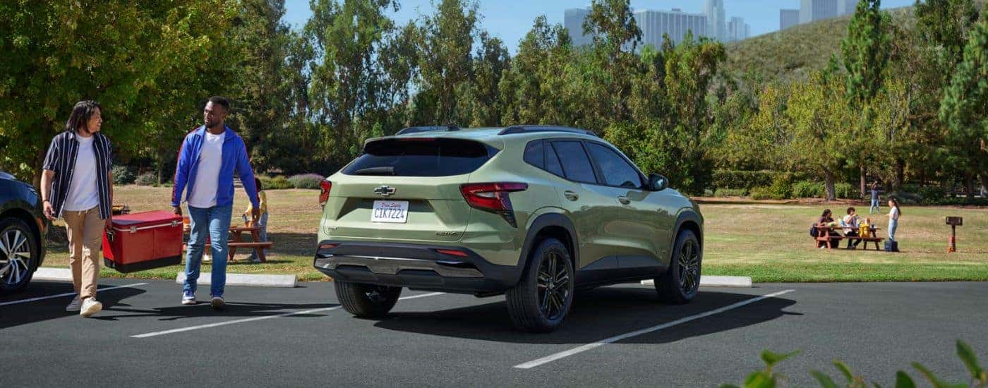 A green 2026 Chevy Trax ACTIV is shown parked by a field with people.