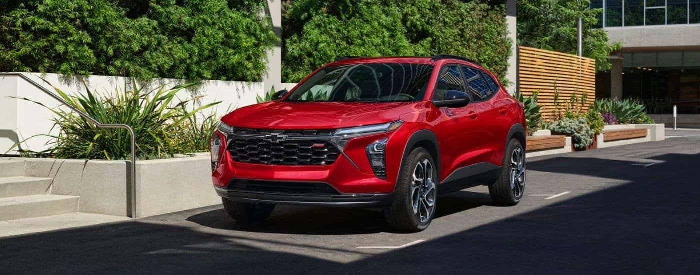 A red 2026 Chevy Trax 2RS shown parked by stairs and bushes.