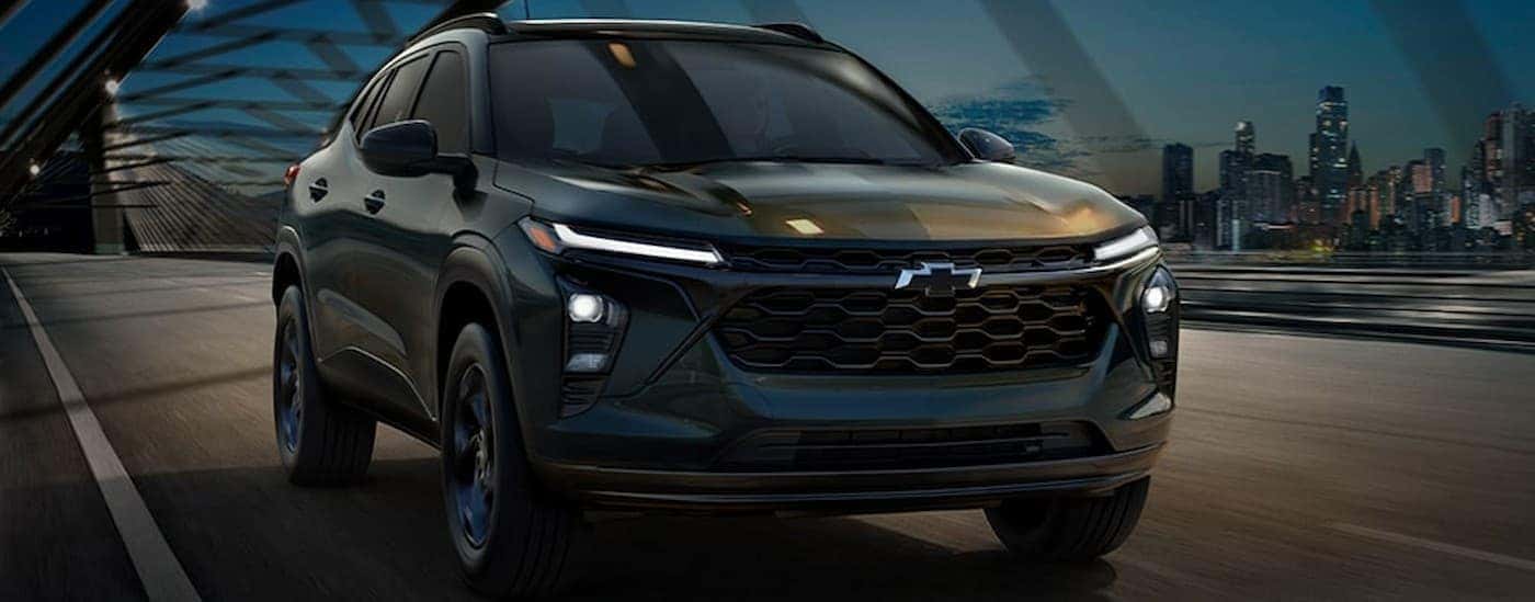 A black 2026 Chevy Trax driving on a bridge.